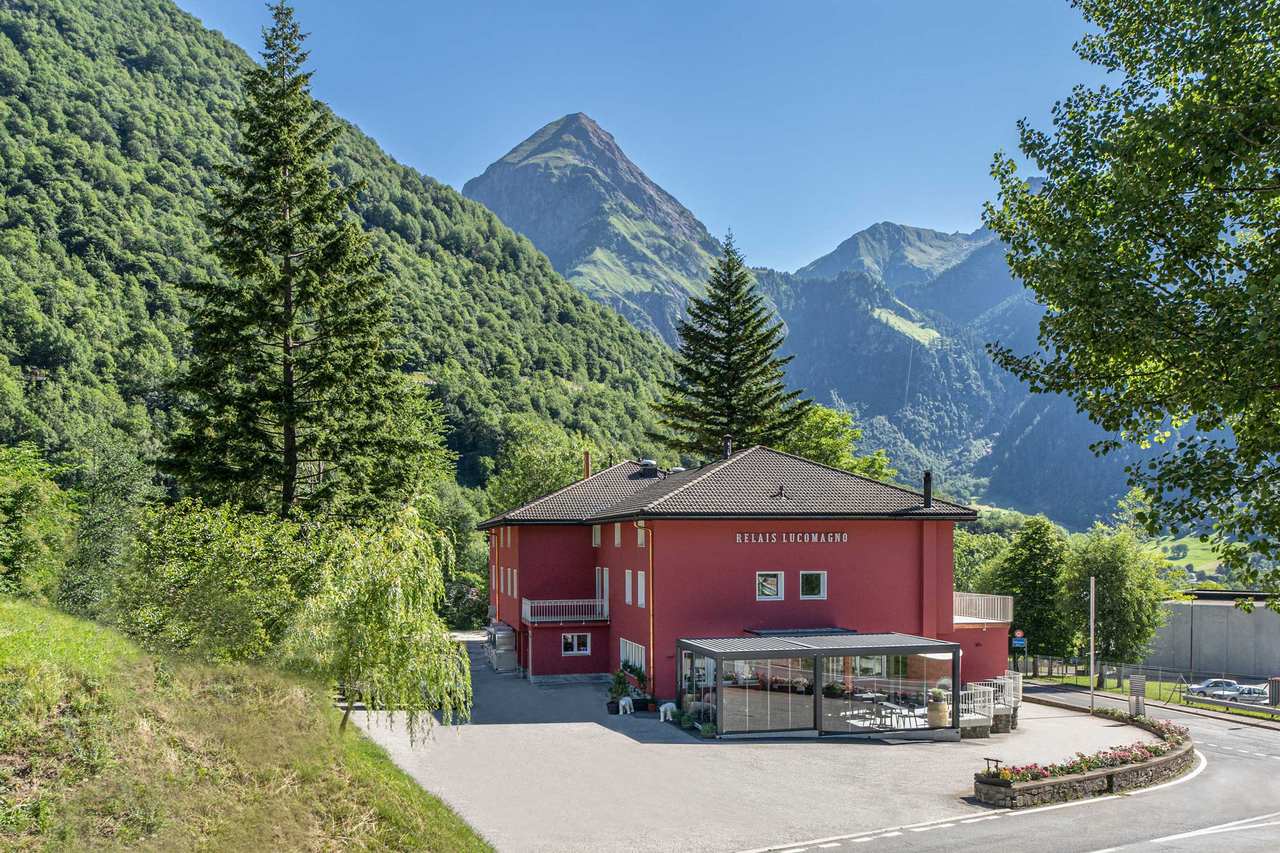 Il Relais Lucomagno a Olivone: l'edificio visto dall'esterno, con le montagne della valle di Blenio sullo sfondo